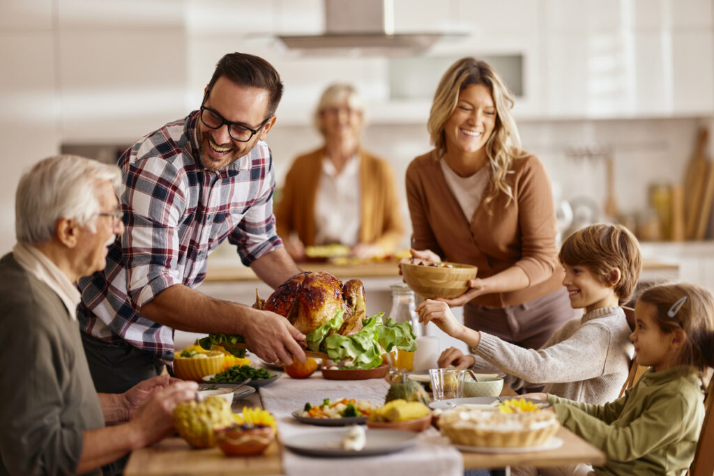 Family serving dinner around a crowded holiday table, creating a warm but noisy setting that can be challenging for hearing aid users.