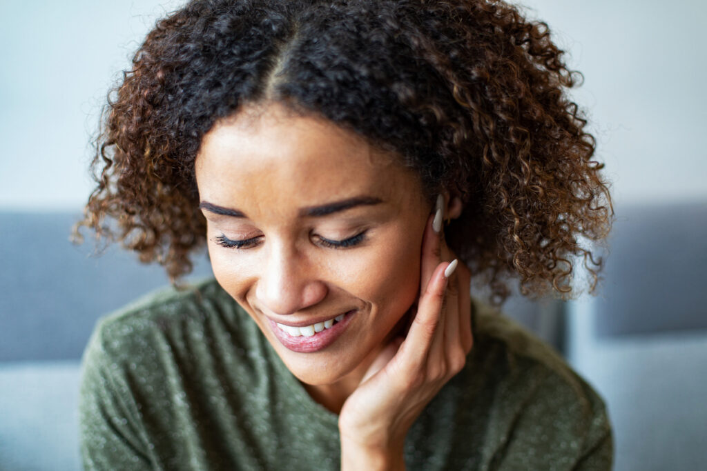 Woman smiling with hand near ear, experiencing tinnitus relief