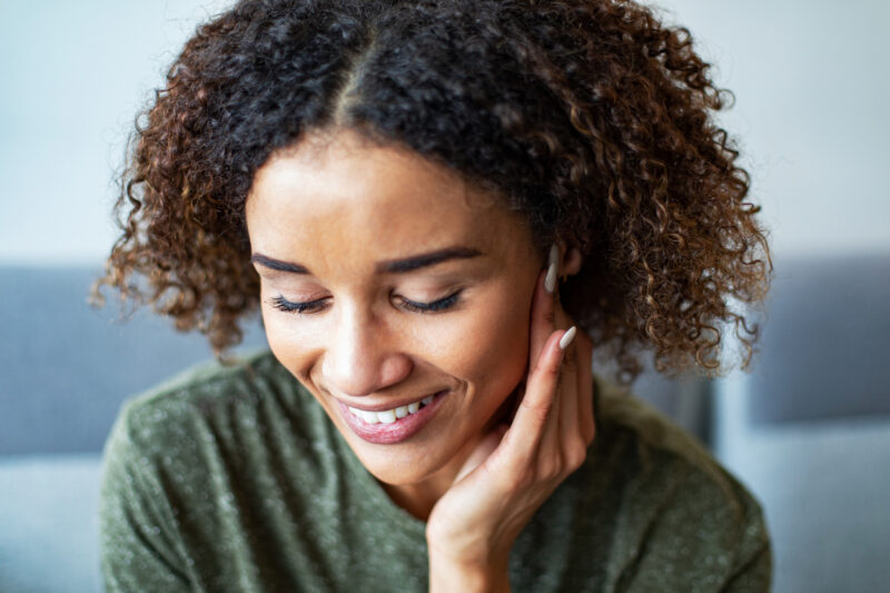 Woman smiling with hand near ear, experiencing tinnitus relief