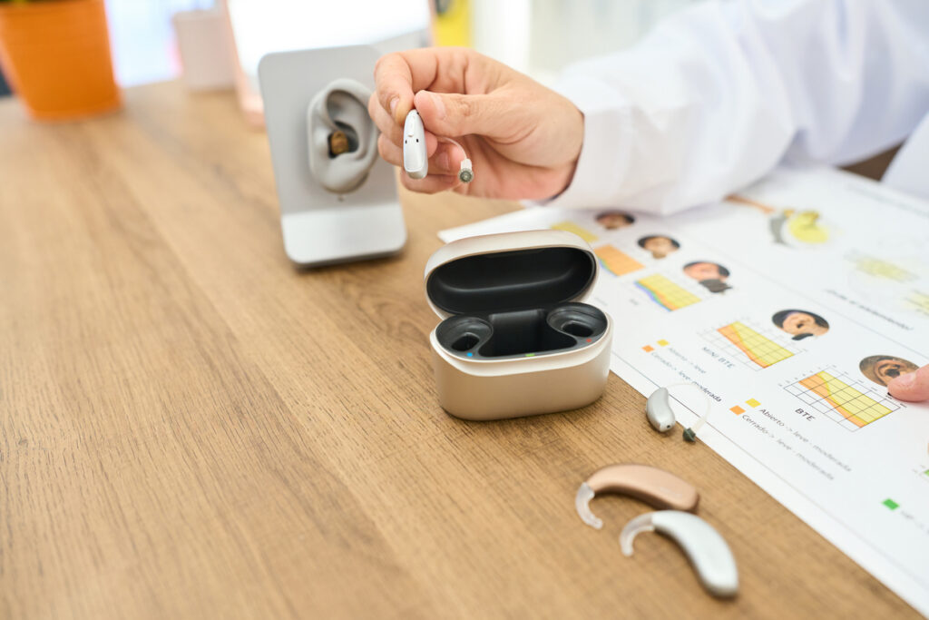 Modern digital hearing aids with rechargeable charging case during professional hearing evaluation