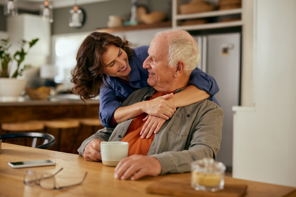 Adult daughter talking with her father at home, noticing the early signs of hearing loss.