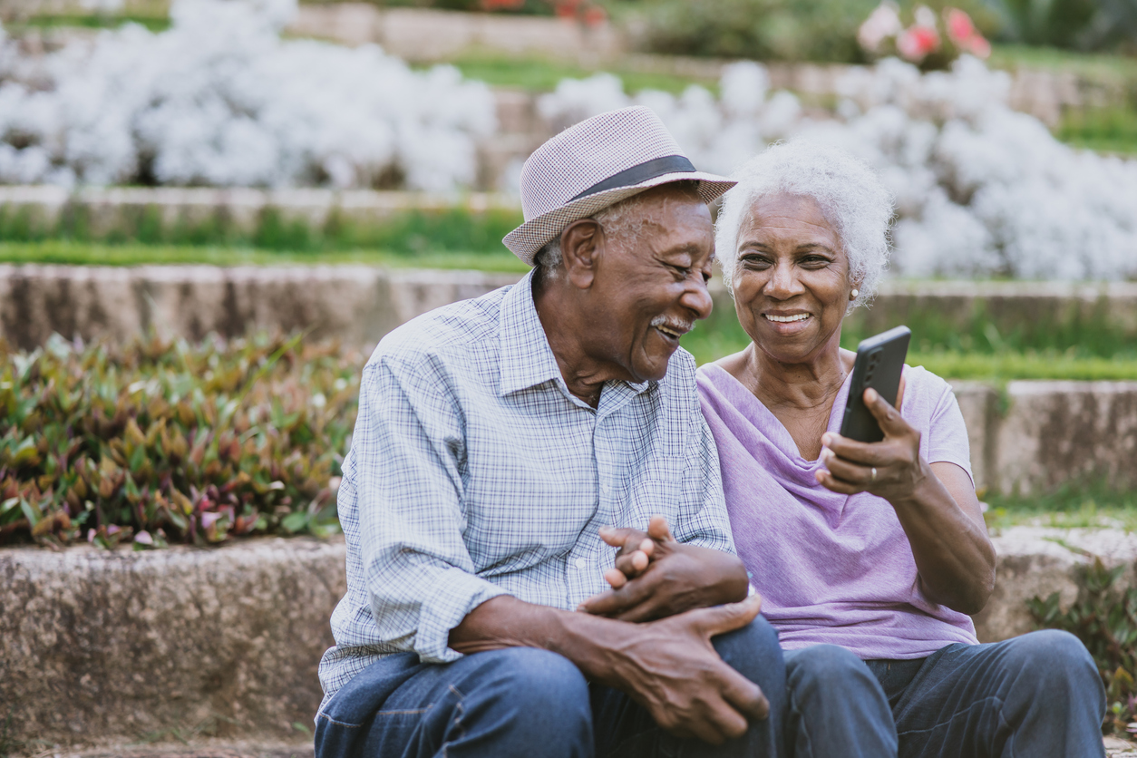 A couple sits together and laughs while experiencing the benefits that come from treating hearing loss early.